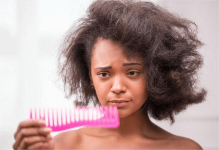 a-woman-with-hair-breakage-looking-at-her-comb